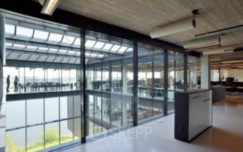 Spacious, modern office building interior at Archangelkade 9, Amsterdam Houthavens showcasing glass walls, natural light, and a large open workspace. Ideal for office space rental.