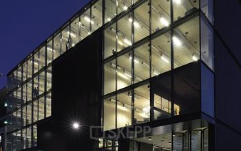 Modern glass-fronted office building at Archangelkade 9, Amsterdam Houthavens, illuminated at night, showcasing a spacious exterior design.