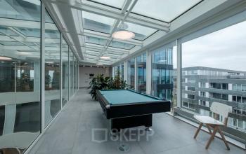 Bright office space with a pool table under a glass ceiling at Pedro de Medinalaan 7, Amsterdam IJburg, available for office space rental.