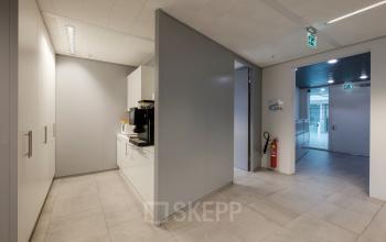 Office space rental at Pedro de Medinalaan 7, Amsterdam IJburg, featuring a modern interior with sleek grey walls and a kitchenette area.