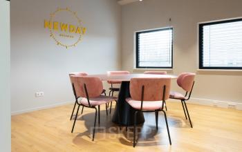 Bright, modern conference room in Amsterdam New-West located at Overschiestraat 63, featuring a round table with stylish pink chairs for office space rental.