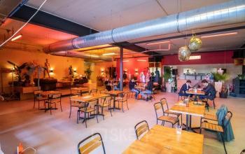 Vibrant interior of an office space in Amsterdam Nieuw-West, featuring eclectic decor and open floorplan for collaborative work. Office space rental available with colorful ambiance and modern seating arrangements.