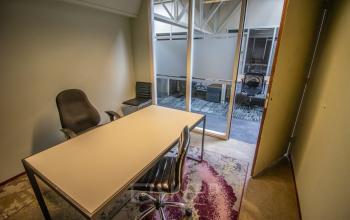 Office space rental at Anthony Fokkerweg 3, Amsterdam Nieuw-West, featuring a minimalist private office with modern seating and a large window overlooking a communal area.
