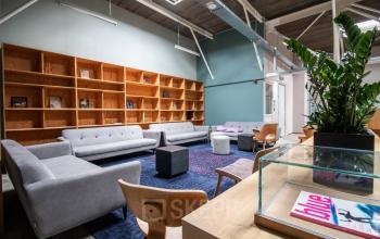 Modern lounge area showcasing sleek furniture, green walls, and ample natural light. Ideal for informal meetings, part of a flexible office space rental in Amsterdam Nieuw-West on Anthony Fokkerweg 3.