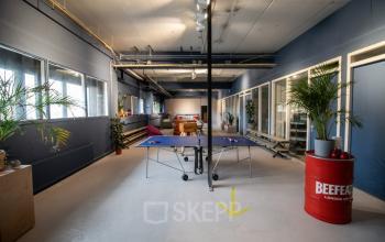 Creative office space for rent at Anthony Fokkerweg 3, Amsterdam Nieuw-West, featuring large windows, vibrant decor, and a playful atmosphere with a ping-pong table, perfect for inspiring productivity and collaboration.