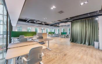 Modern office space at Koningin Wilhelminaplein 1, Amsterdam New-West, featuring an open floor plan with sleek desks and vibrant green accents, ideal for office space rental.