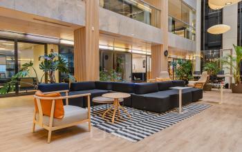 Modern lounge area at Koningin Wilhelminaplein 1 in Amsterdam New-West, featuring stylish seating and natural lighting. Ideal for office space rental with a welcoming environment for relaxed meetings and networking.