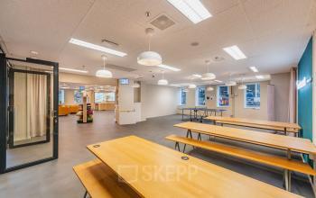 Spacious and modern open floorplan at Koningin Wilhelminaplein 1, Amsterdam New-West, featuring long wooden tables and bright lighting, ideal for office space rental.