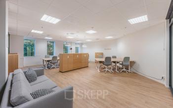 Spacious office to rent at Koningin Wilhelminaplein 1, Amsterdam New-West, featuring modern workspaces with natural light, wooden flooring, and comfortable seating arrangements for collaborative business activities.