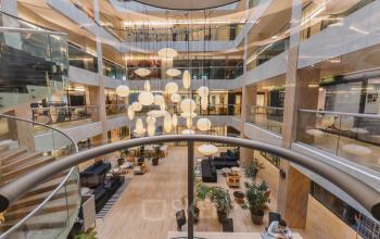 Modern Amsterdam New-West office lobby at Koningin Wilhelminaplein 1 featuring contemporary lighting, abundant natural light, and stylish furniture. Ideal for office space rental with an inviting atmosphere and well-structured layout.