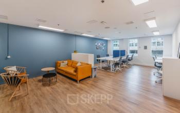 Bright office space with modern furnishings, including desks, chairs, and a lounge area with a sofa, located at Koningin Wilhelminaplein 1, Amsterdam New-West, available for office space rental.