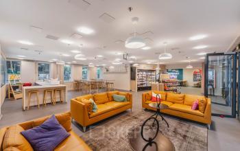 Modern open workspace at Koningin Wilhelminaplein 1, Amsterdam New-West, featuring vibrant seating areas and ample natural light, ideal for office space rental.