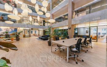 Modern office interior at Koningin Wilhelminaplein 1, Amsterdam New-West, featuring an open floorplan with desks, chairs, and stylish lighting, ideal for office space rental.