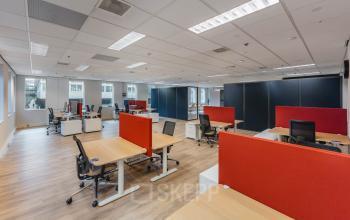 Spacious office with modern furnishings and ergonomic chairs, ideal for office space rental at Koningin Wilhelminaplein 1, Amsterdam New-West. Bright lighting and open layout enhance a productive work environment.