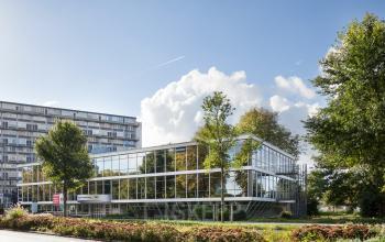 Exterior view of the office building at Baden Powellweg 283/305 in Amsterdam Nieuw-West, reflecting the blue sky and surrounding greenery.