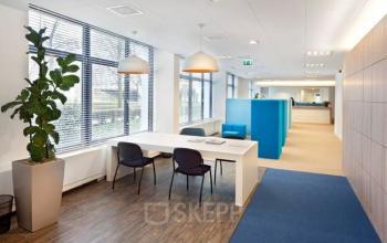 Modern office space at Postjesweg 175, Amsterdam Nieuw-West featuring a bright interior with large windows, a white table, chairs, and a green plant.