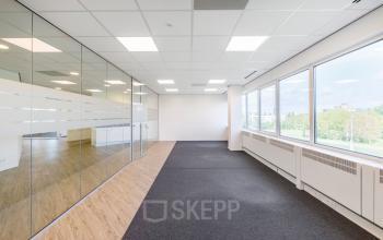Modern, spacious, and brightly lit office space rental at Overschiestraat 61, Amsterdam New-West with large windows, glass partitions, and a mix of carpeting and wood flooring.