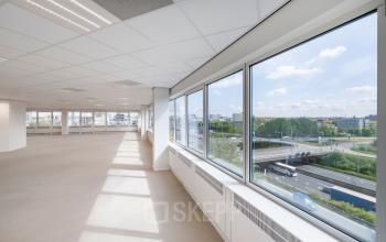 Bright and spacious office to rent at Overschiestraat 61 in Amsterdam Nieuw-West, offering expansive windows with a view of the city.
