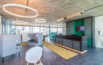 Modern office space for rent at Kraanspoor 12-58, Amsterdam North, featuring contemporary lighting, seating areas, and a reception desk, ideal for office space rental.