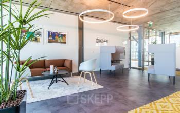 Modern office lounge area with stylish furniture and artwork in Kraanspoor 12-58, Amsterdam North, ideal for office space rental.
