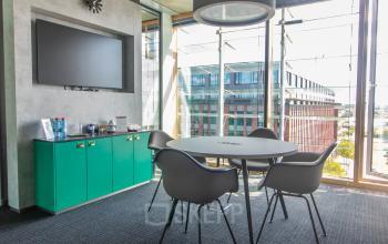 Bright office space with modern furnishings and a large window, available for rent at Kraanspoor 12-58, Amsterdam North. Ideal for meetings or collaborative work with rental options available.