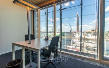 Bright office space at Kraanspoor 12-58, Amsterdam North with a stunning view of the marina, featuring a desk and chairs available for office space rental.