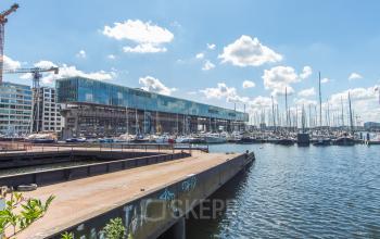 Exterior view of office building at Kraanspoor 12-58, Amsterdam North, with boats docked nearby, indicating a potential office space rental opportunity.