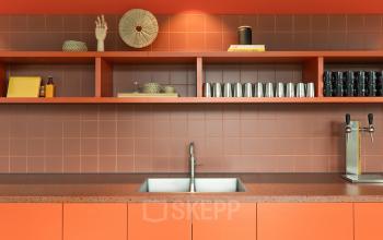 Orange-themed pantry area with a sink, shelves stocked with cups, and decorative items at Papaverhof 58, Amsterdam North, ideal for office space rental.