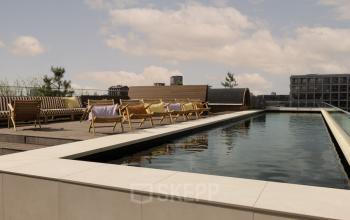 Rooftop terrace with modern wooden chairs and a reflecting pond at Papaverhof 58, perfect for office space rental in Amsterdam North.
