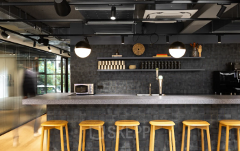 Modern office space rental in Amsterdam North with a sleek kitchenette, featuring a long counter and wooden stools.