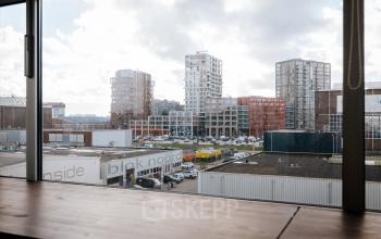 View from an office space rental at TT Vasumweg 44, Amsterdam North, showcasing the surrounding buildings through a large window.