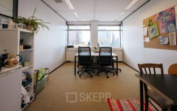 A furnished office space for rent in Amsterdam North at TT Vasumweg 44, featuring a cozy workspace with desks, chairs, and natural light from large windows.