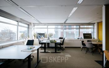 Bright office space with modern furnishings at TT Vasumweg 44, Amsterdam North, ideal for office space rental. Three desks with chairs and large windows provide an inviting work environment.
