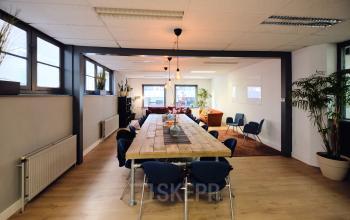 Spacious office area at Hamerstraat 24 in Amsterdam North, featuring a large wooden table, comfortable seating, and ample natural light, ideal for collaborative workspaces. Perfect for office space rental seekers.