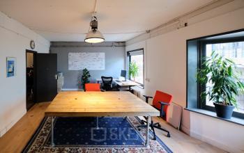 Bright office space at Hamerstraat 24, Amsterdam North, featuring large windows, wooden table, and ergonomic chairs, ideal for office space rental needs.