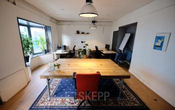 Cozy office space rental at Hamerstraat 24, Amsterdam, featuring a shared workspace with wooden tables, modern chairs, and natural light, perfect for collaboration and productivity.