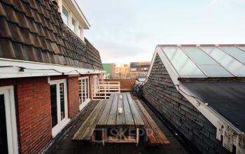 Rooftop terrace at Hamerstraat 24, Amsterdam North, featuring a wooden picnic table and scenic views. Ideal for outdoor breaks. Office space rental available nearby.