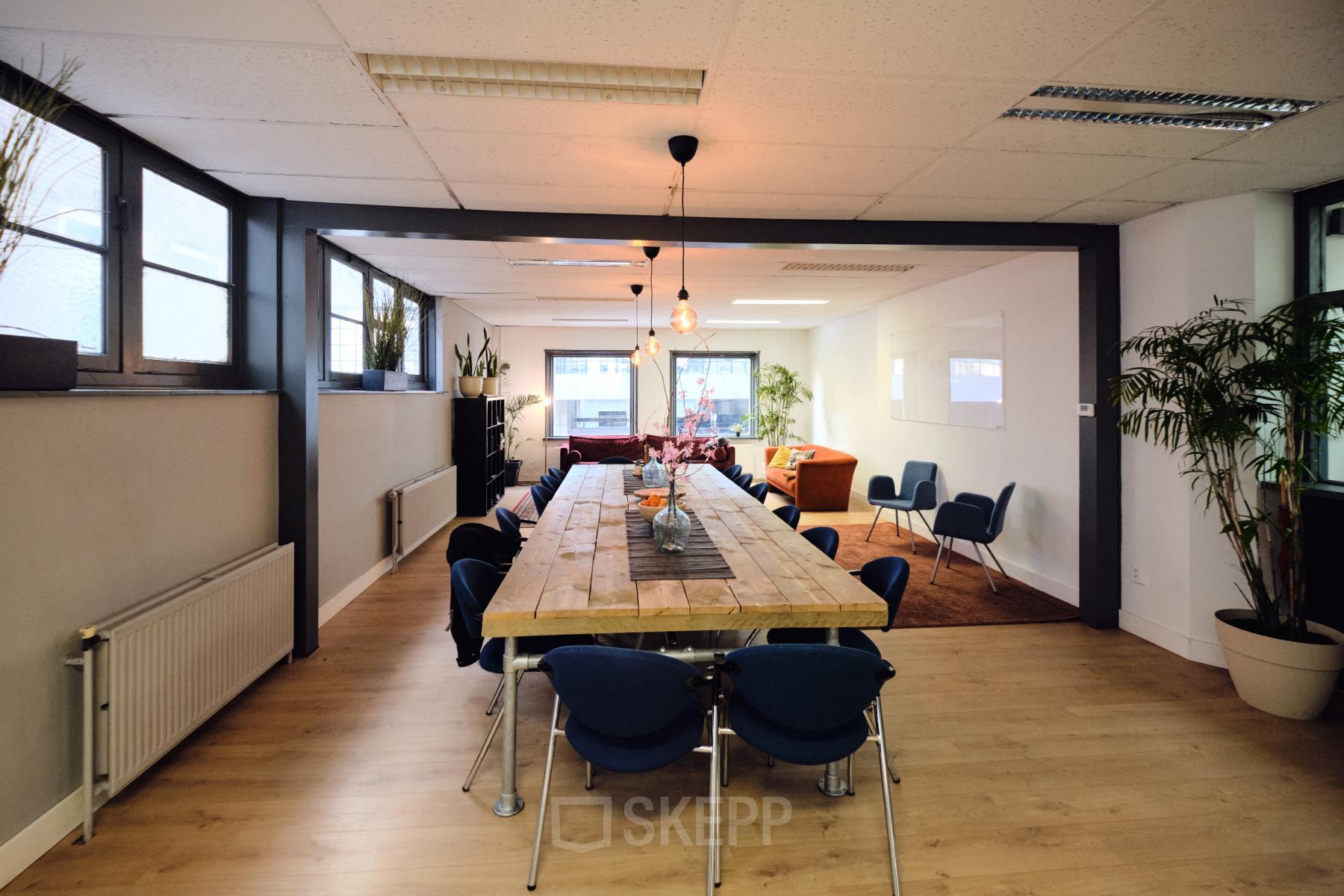 Spacious office area at Hamerstraat 24 in Amsterdam North, featuring a large wooden table, comfortable seating, and ample natural light, ideal for collaborative workspaces. Perfect for office space rental seekers.