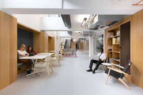 Modern office interior at Mt. Lincolnweg 38-40, Amsterdam North, featuring open workspaces with wooden elements, ample lighting, and colleagues engaged in discussions and laptop work—ideal for office space rental.