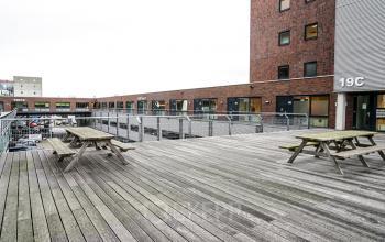 Asterweg 19 Amsterdam North offers an inviting terrace as part of its office space rental, showcasing outdoor benches and a modern building facade.