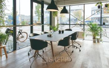 Modern office space rental at Asterweg 19 in Amsterdam North with large windows, stylish furnishings, and plants adding a touch of nature.
