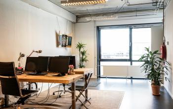 Cozy and well-lit office space rental at Asterweg 19, Amsterdam North, with wooden desks, computers, and potted plants adding a touch of green.