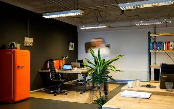 Modern Amsterdam North office space rental at Asterweg 19 with vibrant furniture and a busy professional.