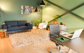 Office space rental at Asterweg 19 in Amsterdam North featuring a neatly organized work desk, comfortable seating, and warm lighting.