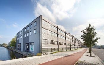 Exterior view of office building at Distelweg 78-80, Amsterdam North, showcasing modern architecture by the canal available for office space rental.