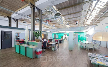 Modern office interior at Distelweg 78-80, Amsterdam North, featuring spacious workstations and a meeting area with natural light for a pleasant office space rental experience.