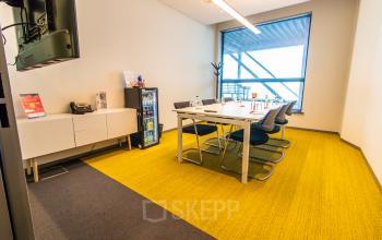 Office space rental at Piet Heinkade 55 in Amsterdam East featuring a modern conference room with a large table and chairs, bright yellow carpet, and a window view.