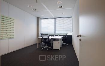 Office space with desks and chairs overlooking a cityscape at Piet Heinkade 55, ideal for those seeking office space rental in Amsterdam East.