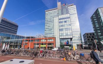 Exterior view of an office building at Piet Heinkade 55, Amsterdam East, featuring a modern glass facade. Ideal for those seeking office space rental in a prime location.