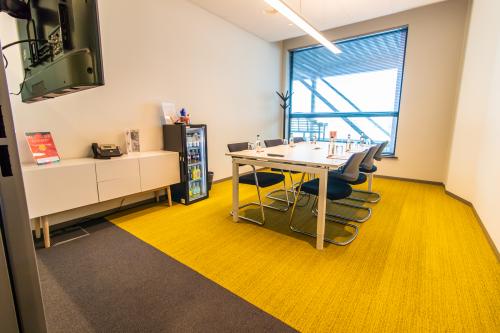 Office space rental at Piet Heinkade 55 in Amsterdam East featuring a modern conference room with a large table and chairs, bright yellow carpet, and a window view.